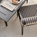 Surya Antibes dining chair with multi-color striped Sunbrella upholstery and black aluminum frame next to a dark patio table.
