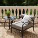 Surya Antibes black aluminum accent chair with striped Sunbrella cushion and white decorative pillow on a patio.