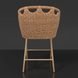 Woven light brown wicker counter stool with a rounded back and light wood-tone legs on a dark background.