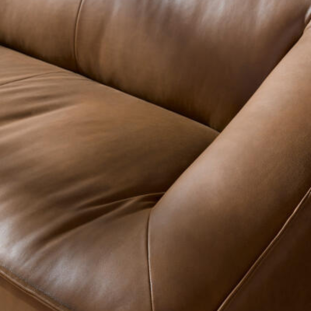 Close-up of a brown leather Surya Alba sofa with cushioned seating and a refined design.