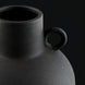 Close-up of a black ceramic decorative accent, featuring a textured finish and a small handle.