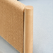 Close-up of a light blue polyester accent chair with a woven tan back and natural wood frame.