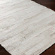 Hand-woven Surya Floria rug in neutral tones, made from recycled PET yarn, on a dark wood floor.