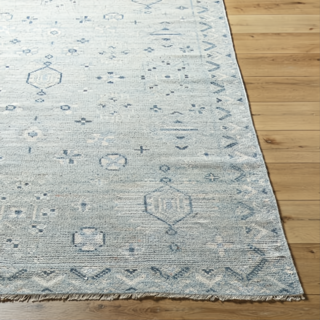 Hand-knotted Surya Almeria ALM2302 low pile rug in multi-tone denim, black, dusty sage, and cream with fringe.