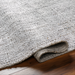Surya Hope hand-loomed flatwoven rug in white, gray, and light slate recycled PET yarn on wood floor.