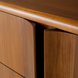Close-up of Grande Collection brown stained poplar dresser with minimalist modern design and curved drawer fronts.