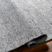 Hand-woven gray Surya Abby ABB-2300 area rug made from recycled PET yarn, partially rolled on a wood floor.