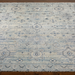 Surya Almeria hand-knotted low pile area rug in multi-tone denim, black, dusty sage, light beige, cream, and burgundy.