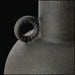 Close-up of a dark, textured ceramic decorative accent with a sculptural, vase-like form and a ring handle.