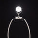 Silver metal lamp harp with a clear glass finial against a dark background.
