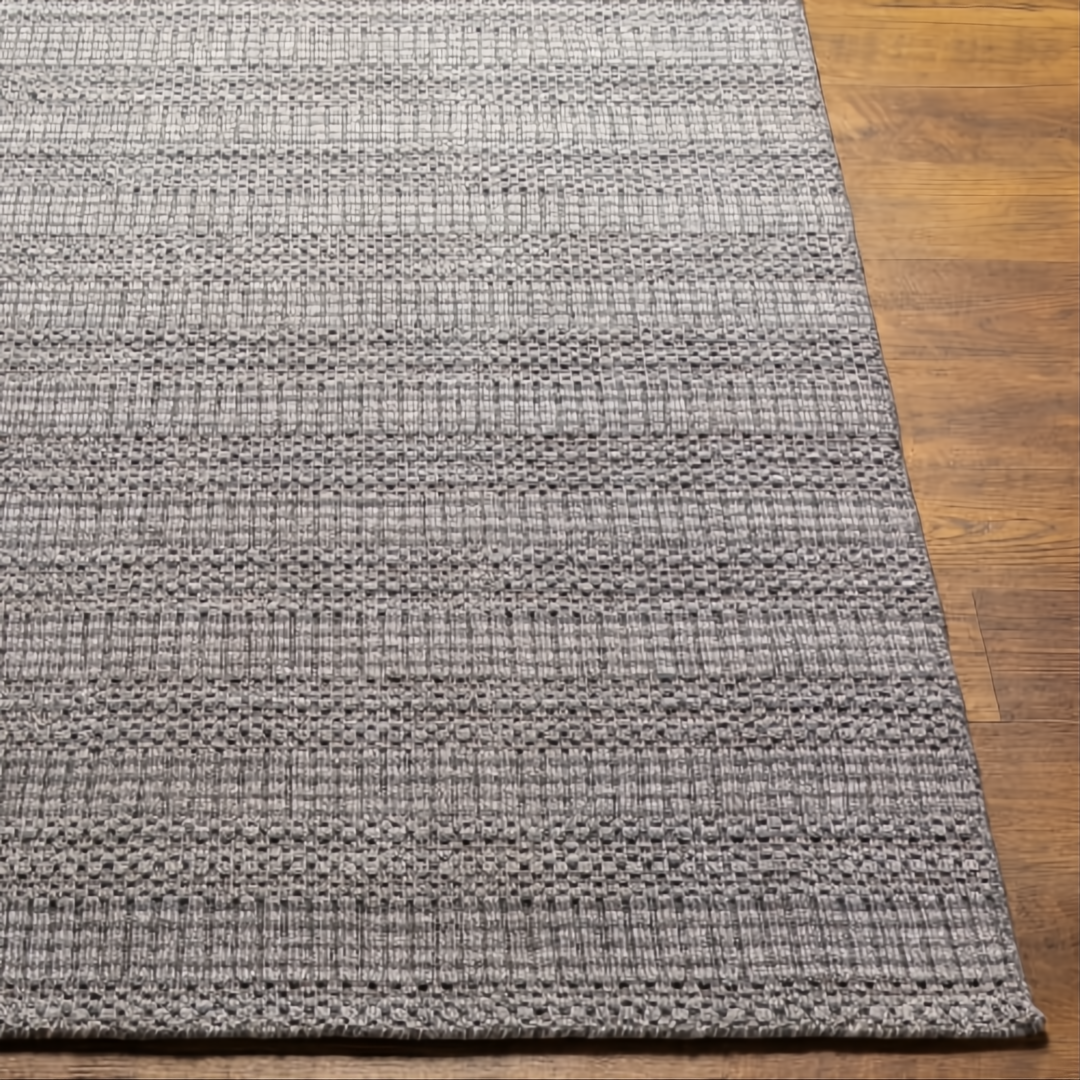 Surya Hickory HCK2304 hand-loomed rug in multi-tone gray, beige, and charcoal recycled PET yarn on wood floor.