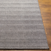 Surya Hickory HCK2304 hand-loomed rug in multi-tone gray, beige, and charcoal recycled PET yarn on wood floor.
