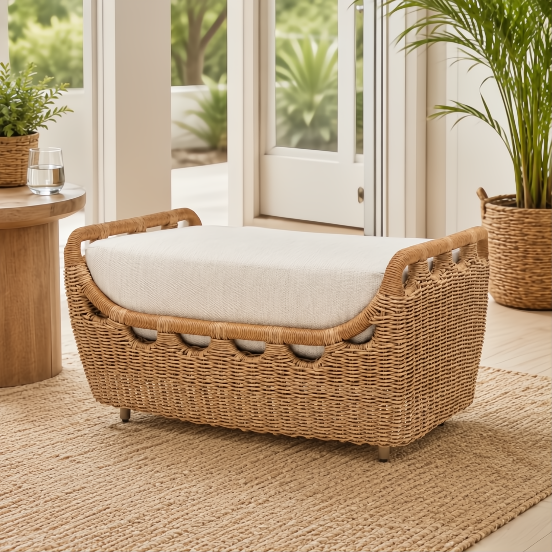 Light brown woven rattan outdoor ottoman with a cream cushion on a natural fiber rug.