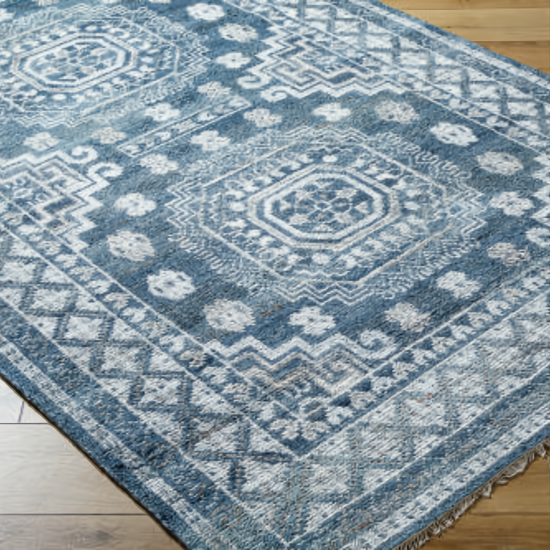 Surya Almeria low pile area rug with blue, gray, and cream geometric patterns on a wood floor.