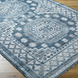 Surya Almeria low pile area rug with blue, gray, and cream geometric patterns on a wood floor.