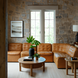 Surya Oryan modular sofa with brown leather upholstery and black base in a living room with stone walls.