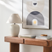 Surya Capelli accent table lamp with a cream ceramic base and fabric shade on a wooden console.