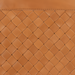 Close-up of a brown leather ottoman with a woven diamond pattern and stitched top edge.