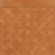 Close-up of a brown leather ottoman with a woven diamond pattern and stitched top edge.