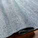 Hand-woven Surya Abby ABB-2302 area rug in light blue recycled PET yarn, partially rolled on a wood floor.