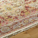 Hand-knotted wool rug with traditional design in plum, gray, burgundy, and olive tones, featuring fringe.