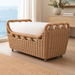 Woven rattan outdoor bench with a light-colored cushion, perfect for coastal or patio settings.