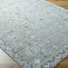 Surya Almeria low pile hand-knotted rug in multi-tone denim, black, dusty sage, light beige, cream, and burgundy.