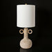 Surya Brava accent table lamp with a textured beige base, two ring handles, a white fabric shade, and gold accents.
