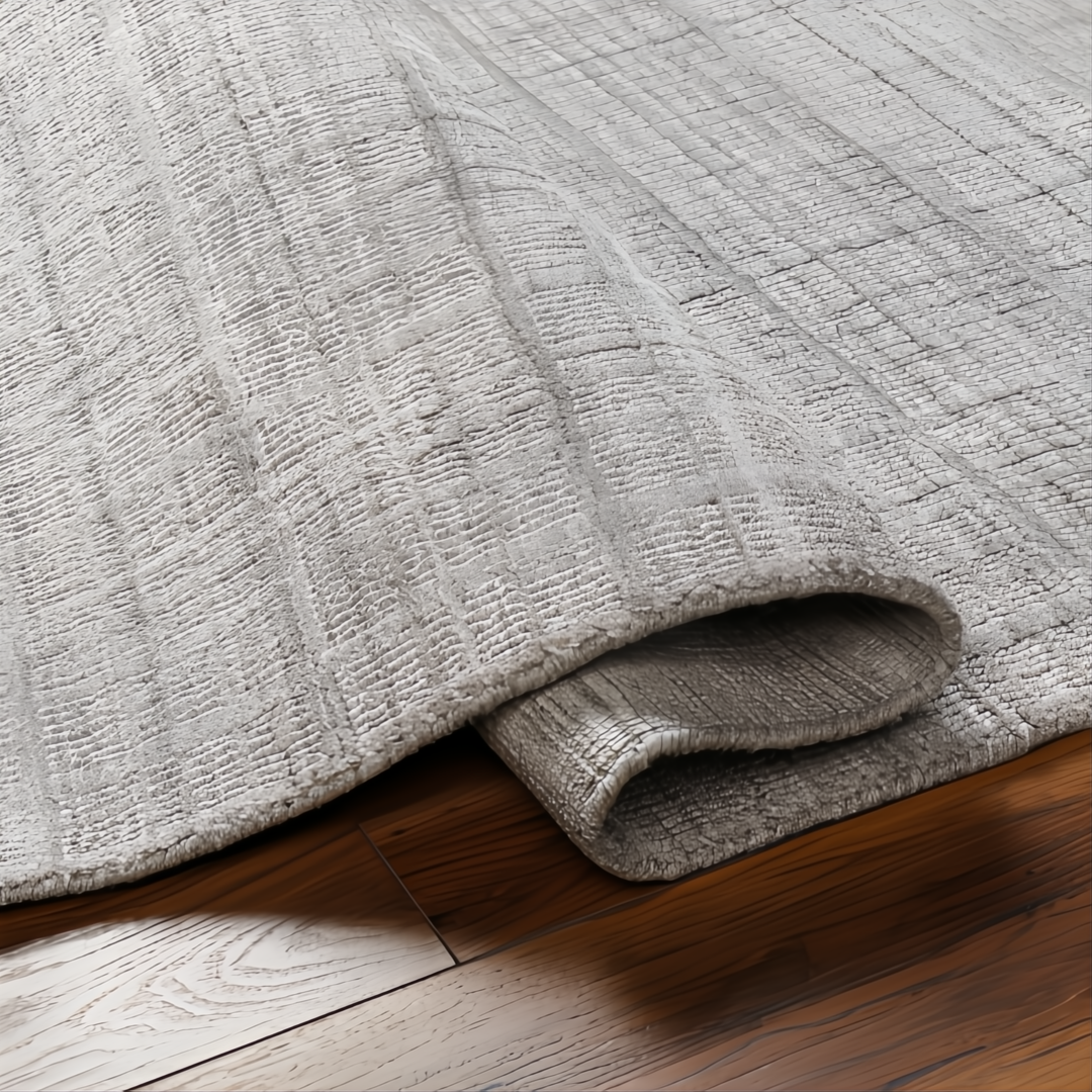 Surya Fresno FNO2302 hand-loomed rug in multi-tone gray recycled PET yarn, partially rolled on wood floor.