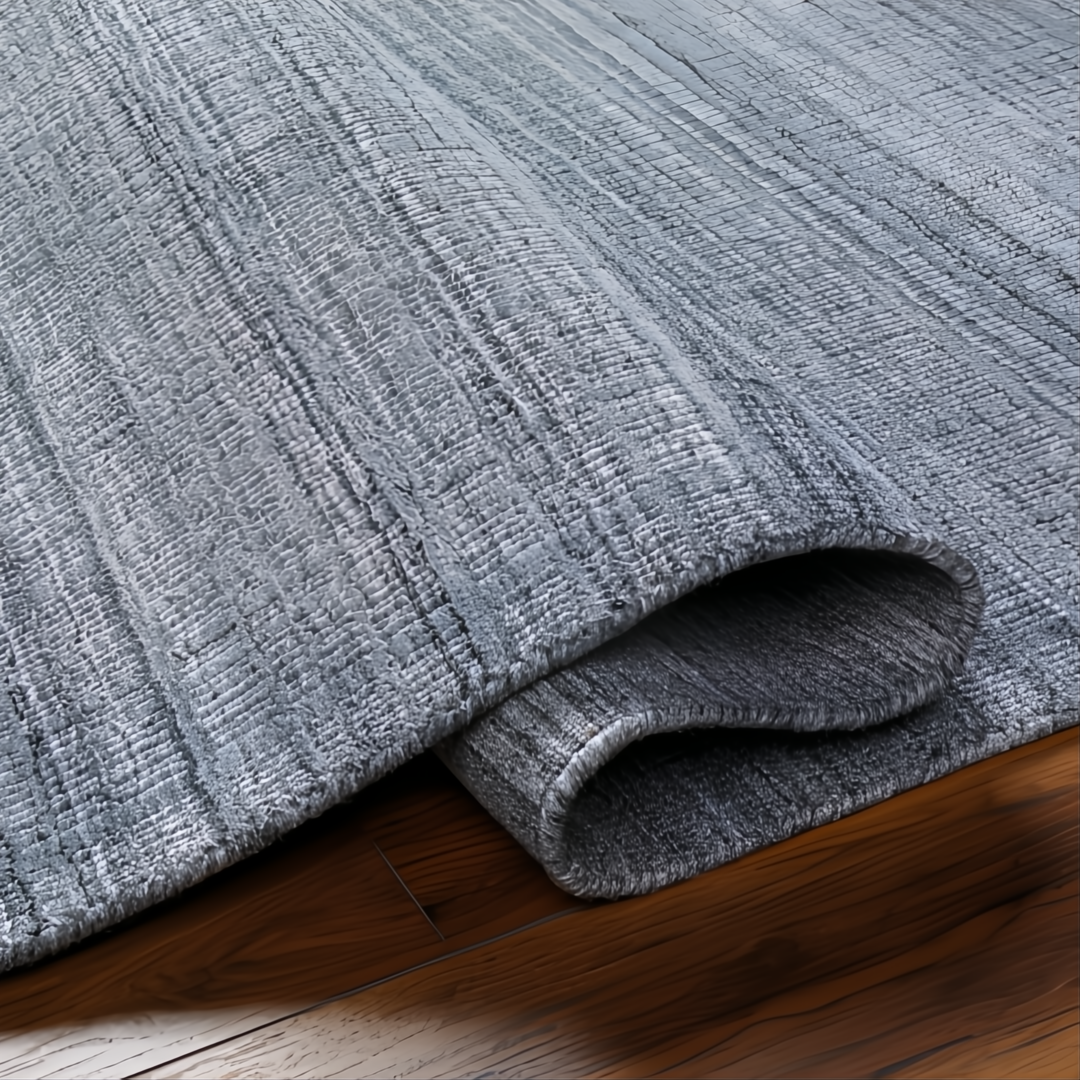 Surya Fresno FNO-2300-P hand-loomed rug in multi-gray recycled PET yarn, partially rolled on wood floor.