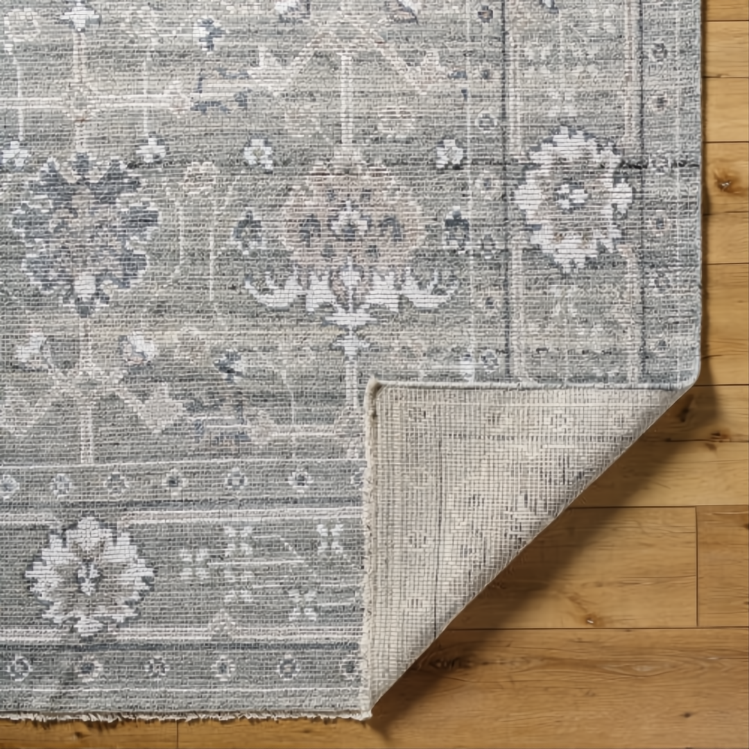 Surya Almeria low pile area rug in medium gray, gray, and cream with intricate floral patterns.