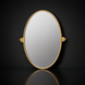 Surya Burnish oval wall mirror with an antiqued gold brass frame on a dark background.