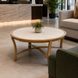 Surya Cape Town 42-inch round outdoor coffee table with a beige stone top and light wood-tone aluminum base.