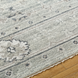 Surya Almeria low pile area rug in medium gray, gray, and cream with subtle pattern and fringe.