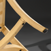 Close-up of a light wood-colored furniture leg with a black foot pad, showing curved and straight elements.