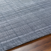 Surya Fresno FNO-2300-P hand-loomed area rug in multi-gray recycled PET yarn on wood floor.