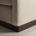 Close-up of a beige polyester swivel chair with a structured silhouette and dark brown rubber wood base.