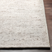 Hand-woven Surya Azalea AZA-2326 rug made from recycled PET yarn, featuring a textured light beige, black, and gray pattern on a wood floor.