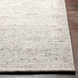 Hand-woven Surya Azalea AZA-2326 rug made from recycled PET yarn, featuring a textured light beige, black, and gray pattern on a wood floor.
