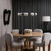 Four Surya Pico Dining Chairs with taupe polyester-linen upholstery and brown rubber wood bases around a round wooden table.