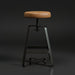 Surya Balin counter stool with brown polished leather seat, black iron base, and spinning adjustable height.