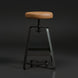 Surya Balin counter stool with brown polished leather seat, black iron base, and spinning adjustable height.
