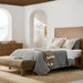 Brown natural Surya Hermosa nightstand with two drawers and metal pulls, next to a bed in a bright bedroom.