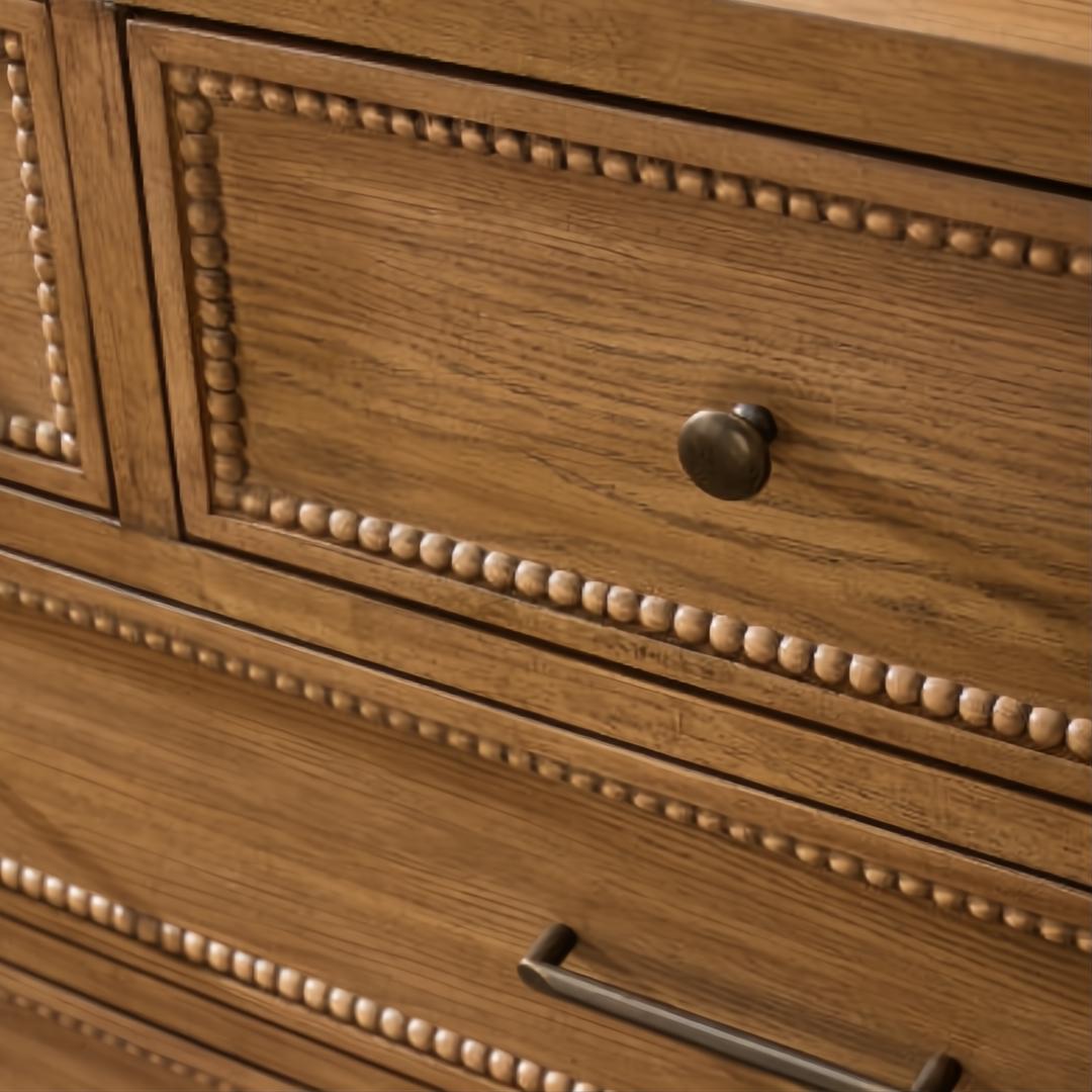 Close-up of a brown painted oak veneer dresser with beaded trim and a dark bronze round knob.