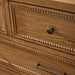 Close-up of a brown painted oak veneer dresser with beaded trim and a dark bronze round knob.