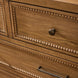 Close-up of a brown painted oak veneer dresser with beaded trim and a dark bronze round knob.