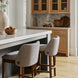 Two light gray upholstered bar stools with wheat-finished beechwood bases at a kitchen island.