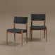 Two Surya Chia dining chairs with brown ash wood frames and black woven seats and backs.