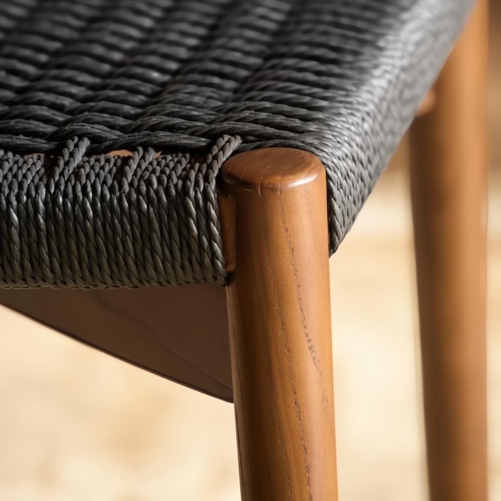 Close-up of a Surya Chia dining chair with a dark woven seat and brown stained ash wood leg.