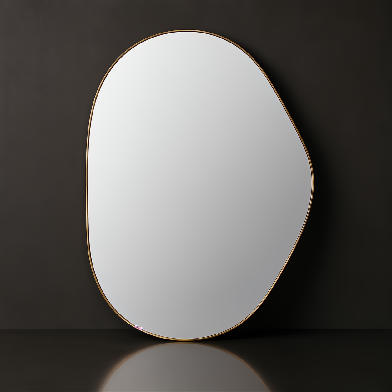 Modern organic-shaped wall mirror with a thin gold frame, reflecting light against a dark background.